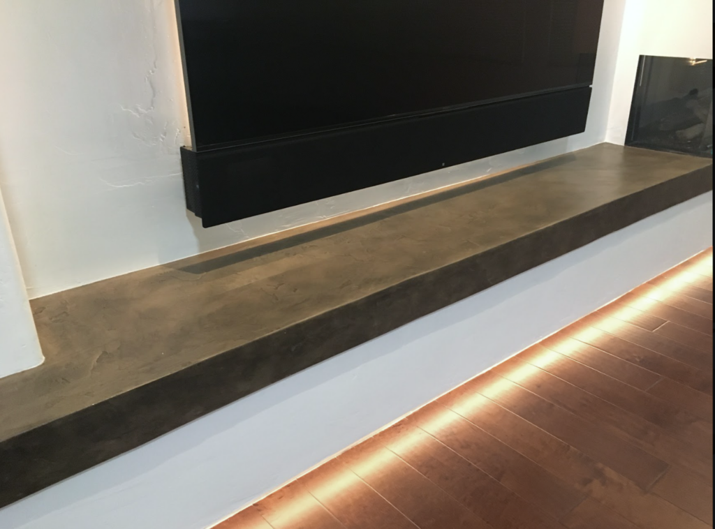 media wall bench and hearth custom with brown and black concrete overlay on white paint walls with  undermount lighting and lighting behind tv