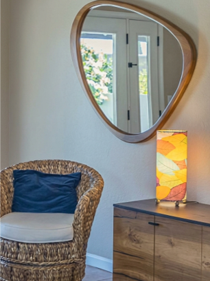Wicker chair, midcentury modern mirror and leaf design accent lamp at secondary seating area in family room
