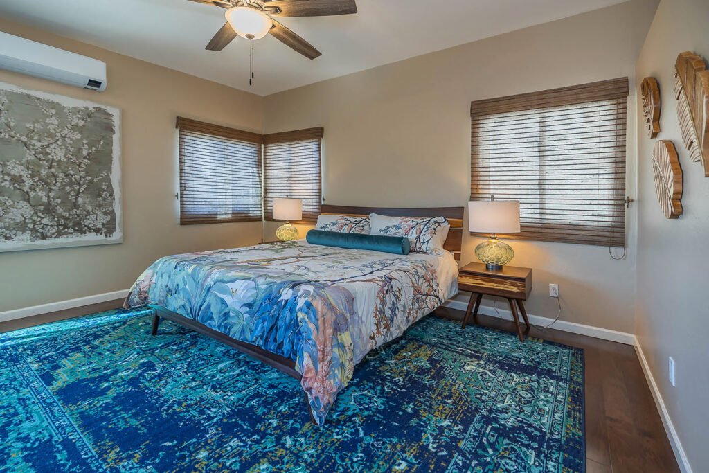 Primary Bedroom in blues and purple with woven wood blinds.