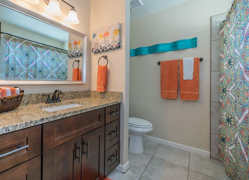 hall bath with bright colored towels, shower curtain and wall art.